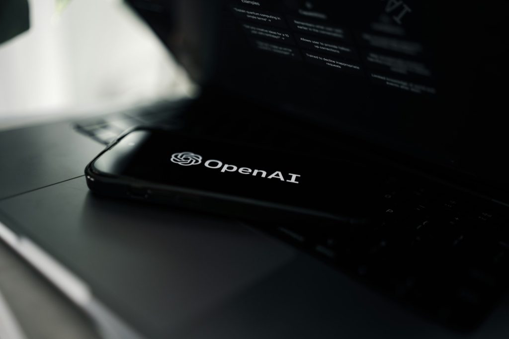 טלפון נייד עם הלוגו של OpenAI מונח על מחשב נייד