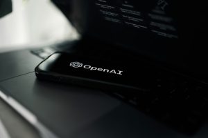 טלפון נייד עם הלוגו של OpenAI מונח על מחשב נייד