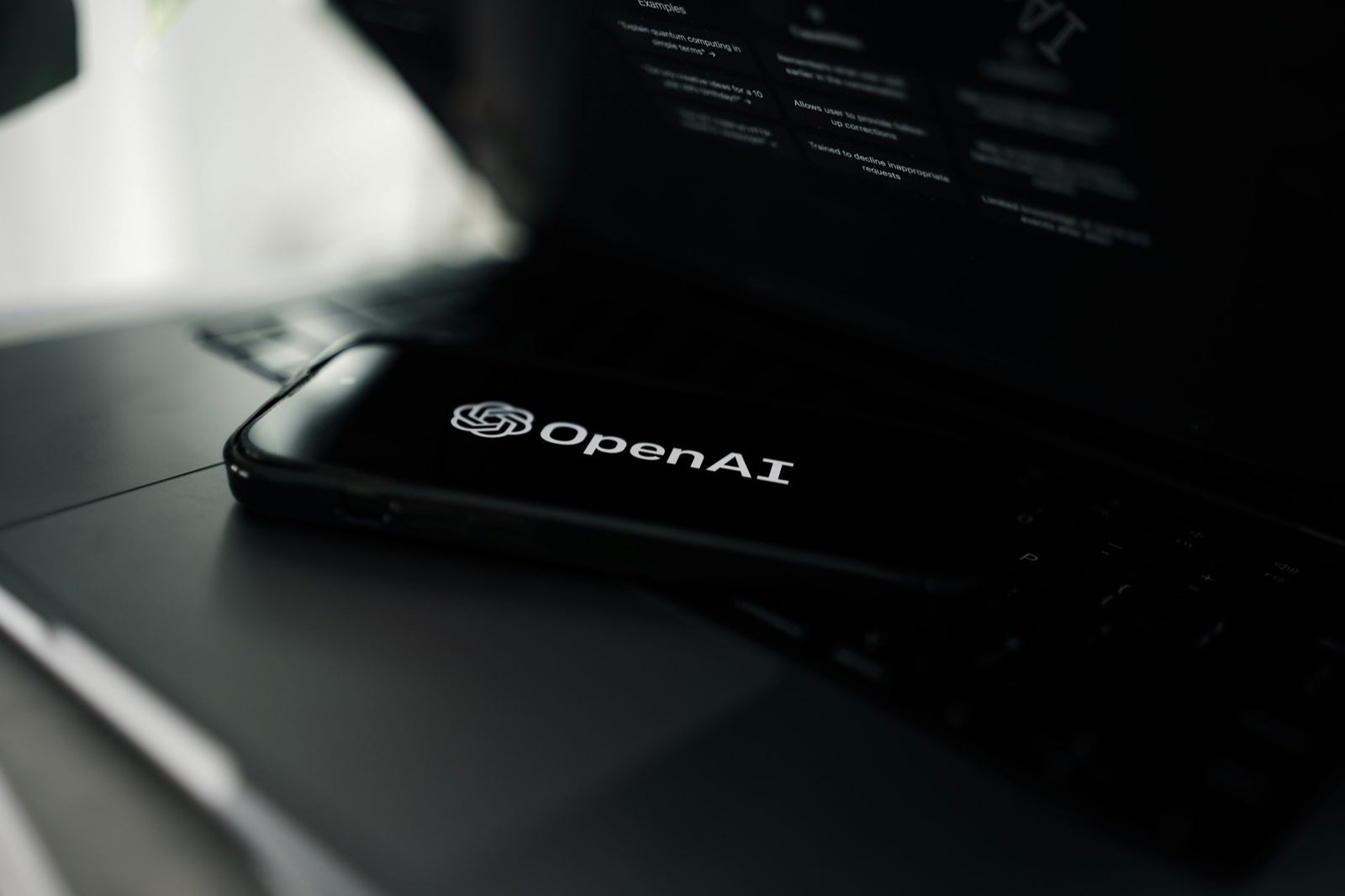 טלפון נייד עם הלוגו של OpenAI מונח על מחשב נייד